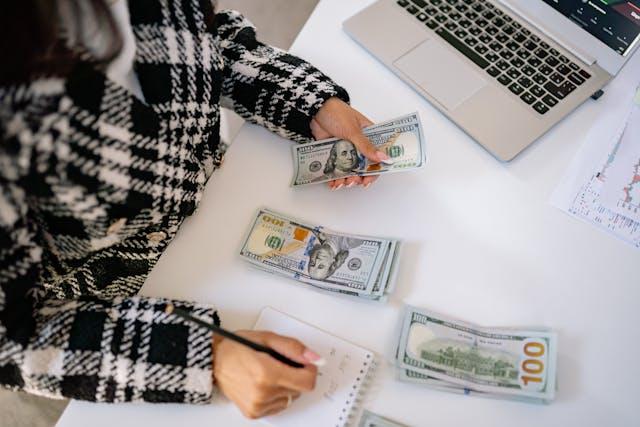 person counting money with notebook and pen